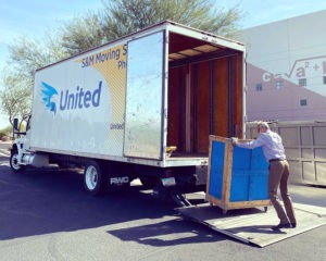 man unloading a crate from an SM Moving Truck