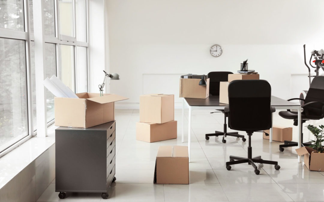 Cardboard boxes with belongings and furniture in new office on moving day for corporate moves